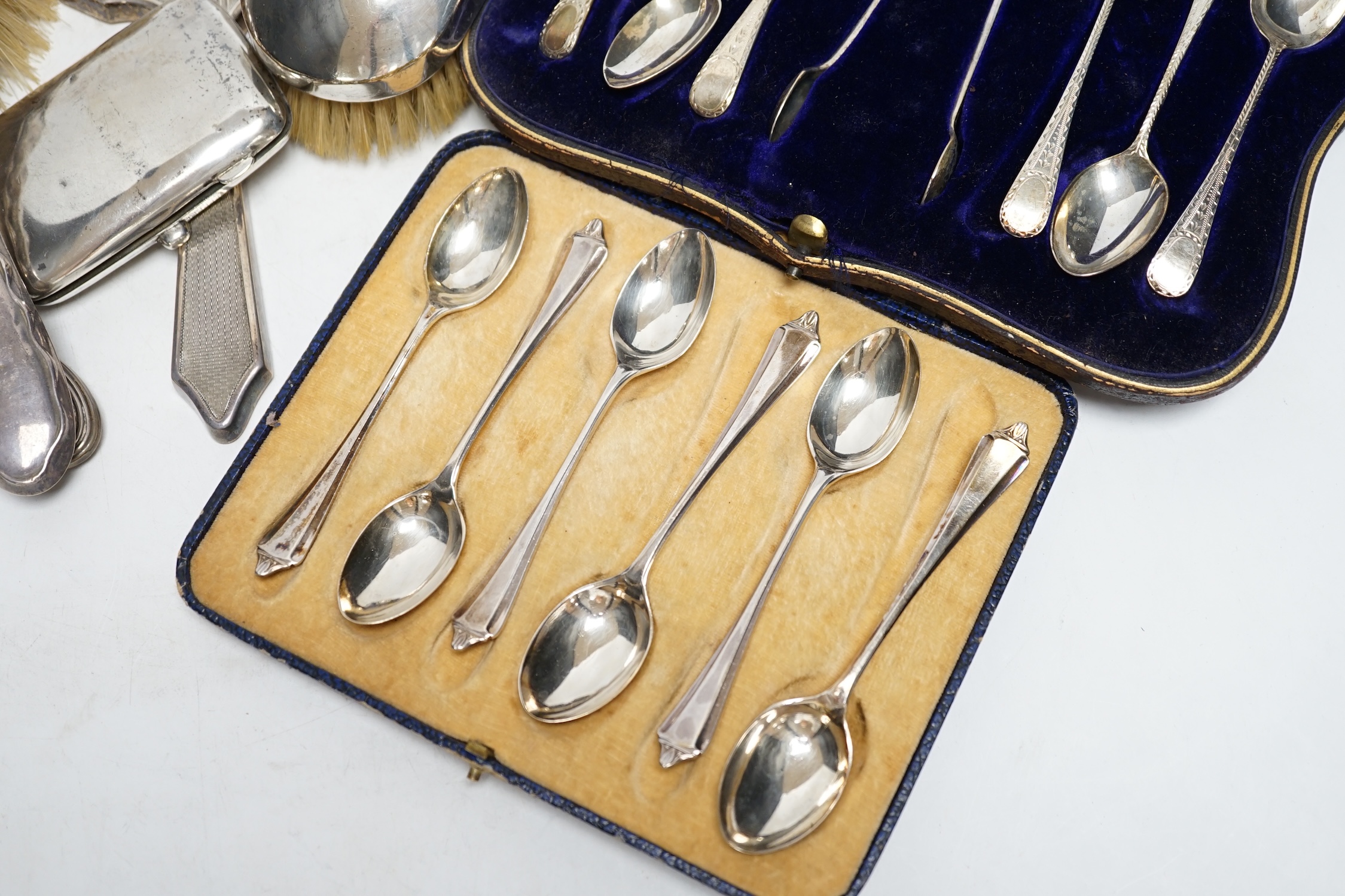 Two cased sets of six silver teaspoons, assorted silver mounted brushes and damaged mirror and a silver cigarette case.